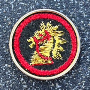 May include: Round embroidered patch with a gold and red design. The patch features a black background with a red border. The central design is a gold and red stylized dragon or mythical creature.