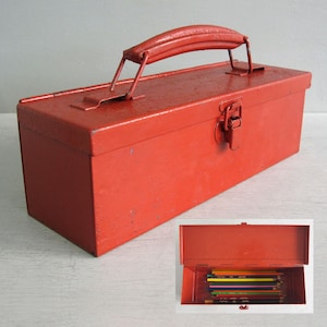 May include: A red metal toolbox with a handle and clasp. The rectangular toolbox has a slightly worn appearance. An inset image shows the open toolbox containing coloured pencils.