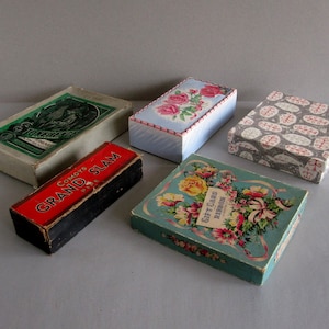May include: Five rectangular boxes of varying sizes and designs. One is a green and white box labelled "Townsend", a black and red box labelled "Comoy's Grand Slam", a light blue box with pink roses, a grey box with red leaf patterns, and a teal box with floral art.