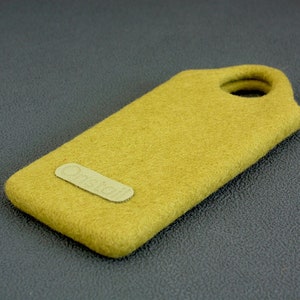 May include: Mustard yellow felt phone case with a rounded top and a hole for a lanyard. A small, rectangular patch with the word "Onstall" is affixed to the front of the case. The case is rectangular and appears to be made of a soft material.