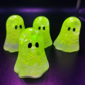 Peut inclure: Quatre petites figurines de fantômes vert vif avec des yeux noirs. Les fantômes sont faits d'un matériau translucide avec des paillettes incrustées à l'intérieur.