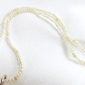 May include: A white pearl necklace with a silver clasp. The necklace is made of small, round pearls and is layered.