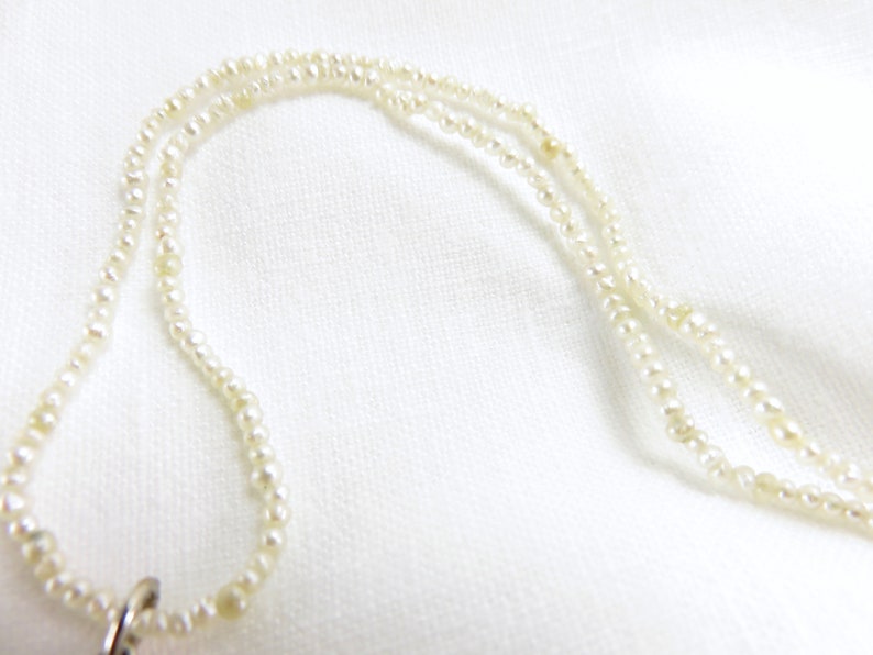 May include: A white pearl necklace with a silver clasp. The necklace is made of small, round pearls and is layered.