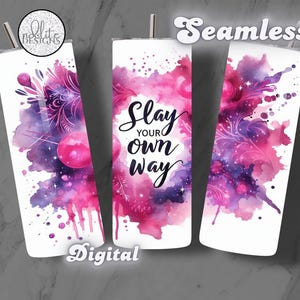 May include: A white tumbler with a pink and purple watercolor design. The design features a galaxy-like pattern with stars and swirls. The text "Slay Your Own Way" is written in black cursive lettering.