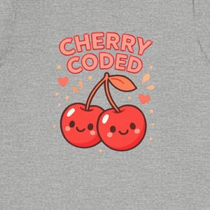 May include: A grey t-shirt with a graphic of two smiling red cherries and the text "CHERRY CODED" in pink. The design includes pink hearts and stars. The shirt is made of a soft material.