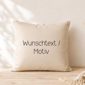 Könnte beinhalten: Ein quadratisches beiges Kissen mit dem mittig aufgedruckten schwarzen Text "Wunschtext / Motiv" auf der Vorderseite. Das Kissen hat einen einfarbigen Stoffbezug und steht aufrecht auf einer ebenen Fläche.
