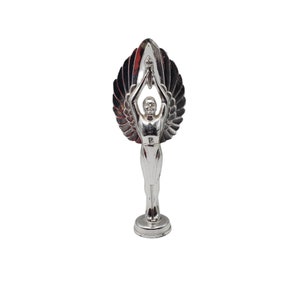 Peut inclure: Trophée en argent avec une figure ailée tenant une torche en l'air. La figure se tient sur une base ronde.