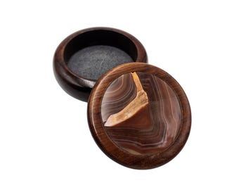 May include: A round wooden box with a lid. The lid is made of dark wood and has a circular inlay of agate. The agate is brown, white, and orange with a swirling pattern.