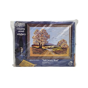 May include: A Paragon Needlecraft creative crewel stitchery kit titled Fall Country Road in a plastic package. The packaging features a landscape illustration of trees with orange and yellow autumn leaves along a dirt path, designed for a 16 by 24 inch frame.