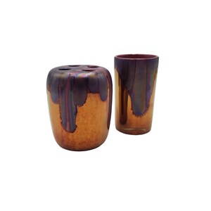 May include: Two iridescent ceramic vases, one tall and cylindrical, the other shorter and rounder, with a metallic finish in shades of purple, orange, and gold.