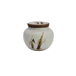 May include: A white ceramic jar with a brown lid and a brown and white abstract design. The jar has a rounded shape and a smooth surface.