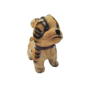 May include: A plush toy dog with brown and black stripes, wearing a brown leather collar. The dog has a brown nose and black eyes.