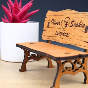 May include: A small wooden bench with a carved heart and the names "Oliver & Sophia" and the date "25/05/2025".