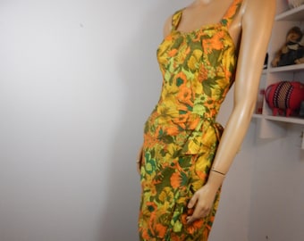 May include: A vintage floral print dress in shades of orange, yellow, and green. The dress features a fitted bodice with spaghetti straps and a knee-length skirt. The fabric has a textured appearance, and the dress is displayed on a mannequin.