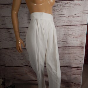 May include: Cream-colored high-waisted pants with pleats. The pants have a wide waistband and a straight leg design. The fabric appears to be a lightweight material, suitable for warmer weather. The pants are displayed on a mannequin.