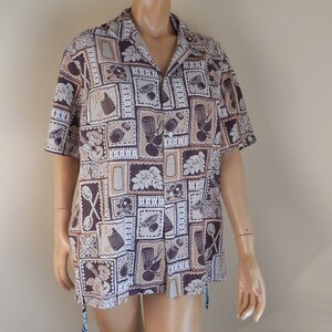 May include: Short-sleeved button-down shirt with a repeating pattern of brown, tan, and white squares. Each square features a different design, including musical instruments, leaves, and kitchen utensils. The shirt has a collared neckline.