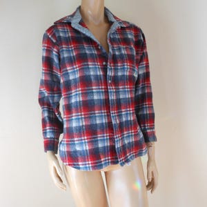 May include: A red, white, and blue plaid flannel shirt with a gray collar. The long-sleeved shirt is buttoned down the front and has a classic, casual style. The shirt is displayed on a mannequin.