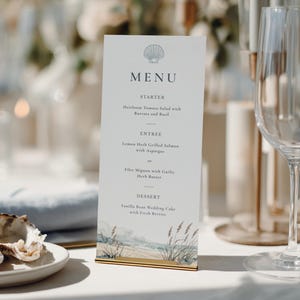 May include: A vertical white menu card featuring a seashell icon at the top, the word MENU, and a list of courses including Starter, Entree, and Dessert. The bottom of the card displays a watercolour illustration of a beach with tall grass.