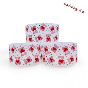 May include: Three white gift boxes with a pink teddy bear and red heart pattern. The boxes are stacked on top of each other. The text "matching bow" is written in red at the top of the image.