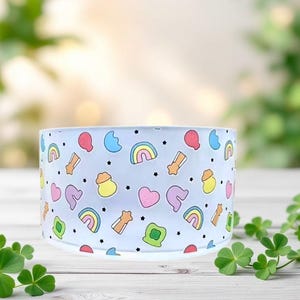 May include: A clear glass bowl with a white background and a rainbow, star, heart, and pot of gold pattern.