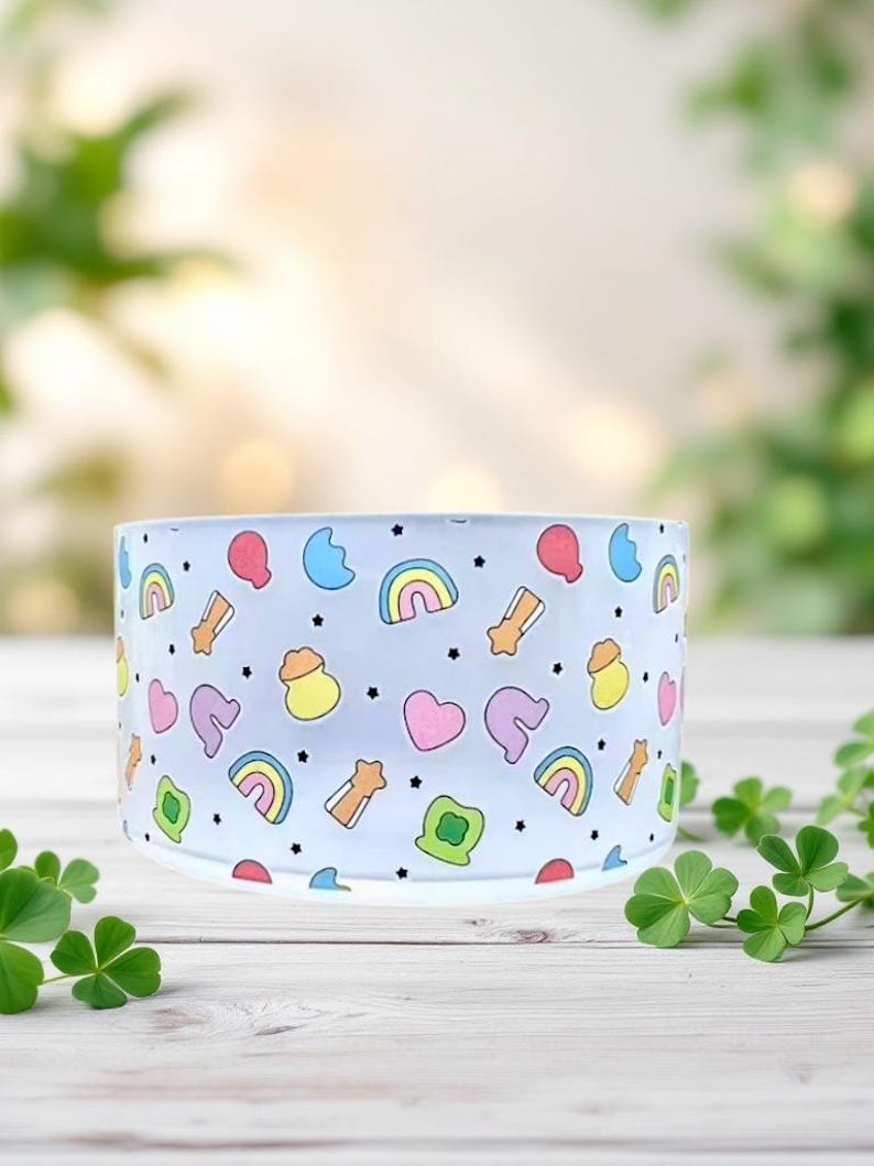 May include: A clear glass bowl with a white background and a rainbow, star, heart, and pot of gold pattern.