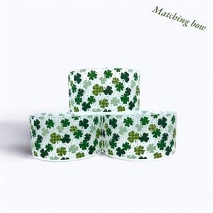 May include: Three white ribbon spools with a green shamrock pattern. The ribbon is printed with green shamrocks on a white background. The text "Matching bow" is visible in the top right corner of the image.
