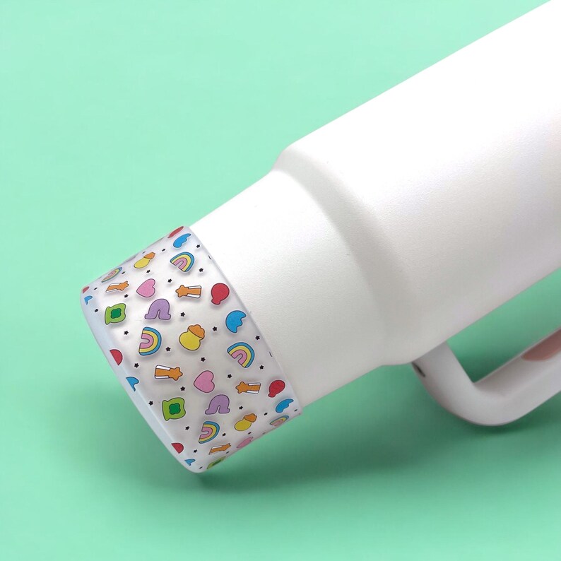 May include: White insulated bottle with a colorful patterned lid. The lid features a repeating pattern of rainbows, hearts, stars, and other small shapes in various colors.