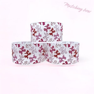 May include: Three white plastic spools with a pink and red bow pattern. The spools are stacked on top of each other. The text "Matching Bow" is written in pink at the top of the image.