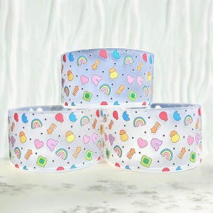 May include: Three clear plastic cups with a rainbow, star, and heart pattern. The cups are stacked on top of each other.