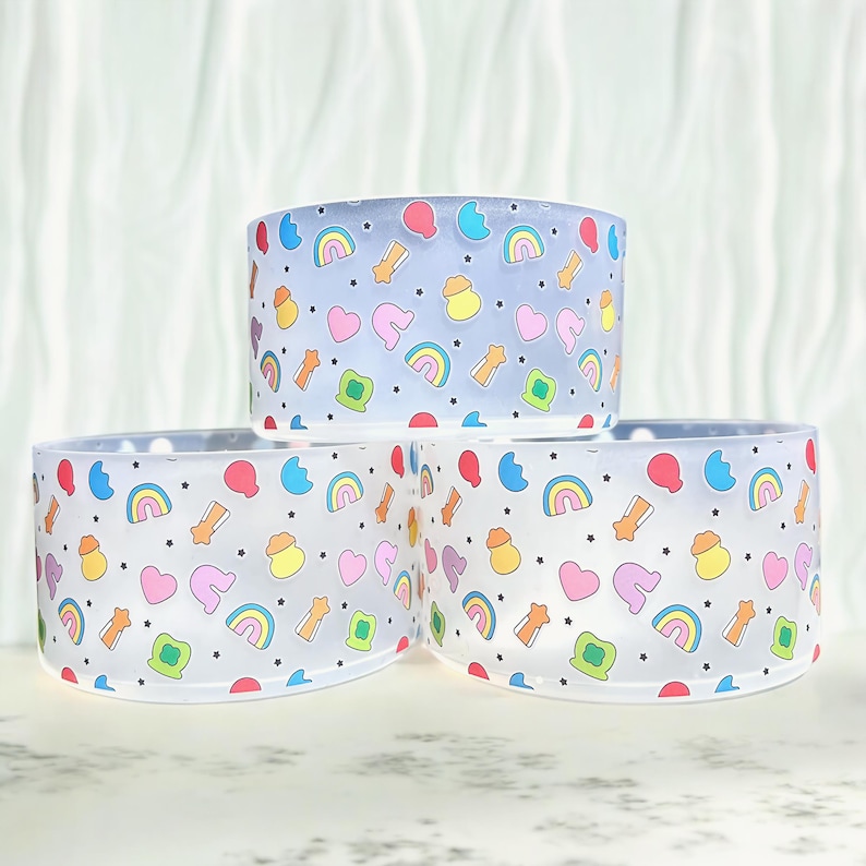 May include: Three clear plastic cups with a rainbow, star, and heart pattern. The cups are stacked on top of each other.