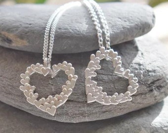 May include: Two silver necklaces with heart-shaped pendants. Each pendant is made of many smaller hearts.