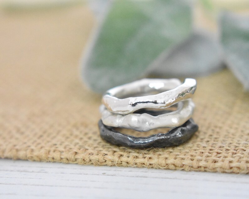 May include: Three silver rings stacked on top of each other. The top two rings are smooth and the bottom ring is textured.