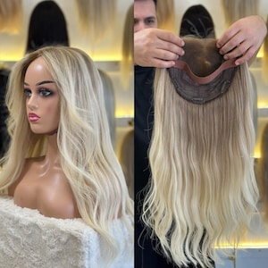 Pode incluir: Uma peruca loira com cabelo longo e ondulado é exibida em uma cabeça de manequim. A peruca tem uma linha de cabelo de aparência natural e uma mistura de tons loiros claros e escuros. Outra imagem mostra a parte inferior da peruca.