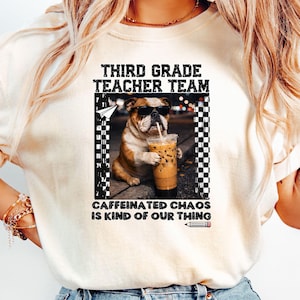 Könnte beinhalten: Ein cremefarbenes T-Shirt mit einer Grafik eines Bulldogs, der eine Sonnenbrille trägt und einen Eiskaffee hält. Der Text lautet THIRD GRADE TEACHER TEAM und CAFFEINATED CHAOS IS KIND OF OUR THING, ergänzt durch ein Papierflugzeug und einen Bleistift.