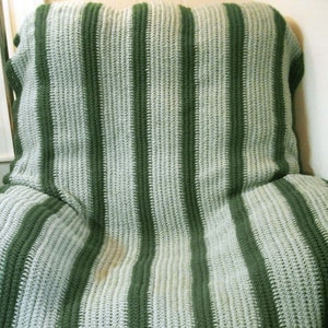 May include: A green and white striped crocheted throw blanket. The blanket is made with a simple stitch and has a relaxed, casual look.