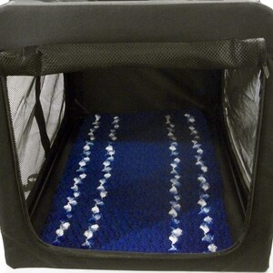 May include: Black soft-sided pet carrier with a blue and white patterned bed inside. The carrier has a mesh window and a zippered top.
