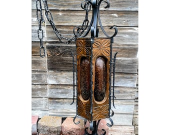 May include: A vintage wood and metal chandelier with a brown wood frame and black metal accents. The chandelier has a square shape and features a decorative design.