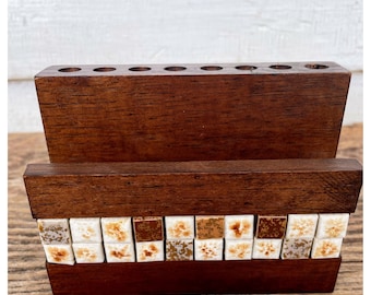 May include: A wooden pencil holder with a decorative tile border. The tile border is made of small white and brown squares with a floral pattern.