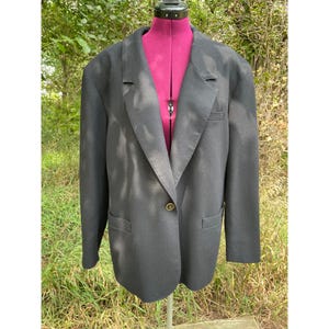 May include: A black blazer with a single gold button closure. The blazer has a notched lapel and a relaxed fit.