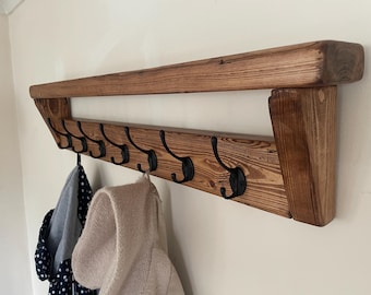 Perchero rústico de madera con estante, ideal para la entrada de una casa de campo, con ganchos.