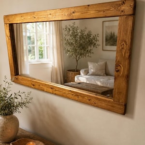 May include: A rectangular wall mirror featuring a thick, natural-toned wooden frame with visible wood grain and knots. The frame has a warm, medium-brown finish and is constructed with straight, sturdy edges that surround a clear, reflective glass surface.