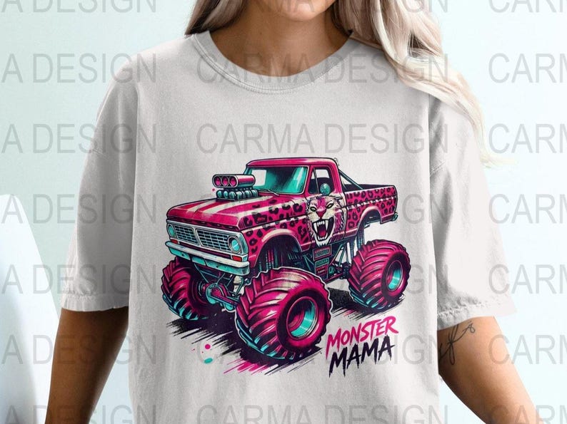 Puede incluir: Una camiseta blanca con un cami&oacute;n monstruo rosa con un dise&ntilde;o de estampado de leopardo. El cami&oacute;n tiene ruedas grandes y el texto "Monster Mama" est&aacute; impreso debajo del cami&oacute;n.