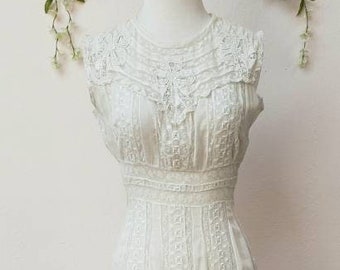 May include: A white lace dress with a high neckline and a fitted bodice. The dress has a full skirt with layers of lace and a scalloped hem.