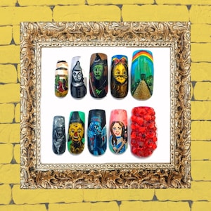 May include: A set of ten painted fingernails featuring characters and scenes from the Wizard of Oz. The nails are painted with images of the Wicked Witch of the West, the Scarecrow, the Tin Man, Dorothy, the Yellow Brick Road, and a red ruby slipper.