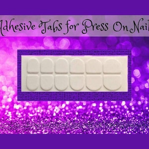 May include: A sheet of adhesive tabs for press-on nails. The tabs are white and arranged in a grid pattern on a white background.