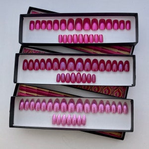 Three rectangular boxes contain individual sets of pink press on nails in square, oval and coffin shapes on  white background.