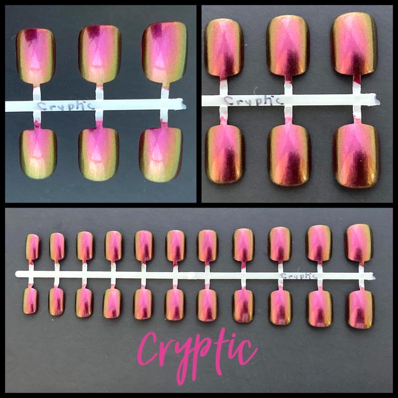 K&ouml;nnte beinhalten: Ein Set mit 20 falschen N&auml;geln mit holografischem Finish. Die N&auml;gel sind eine Mischung aus Pink und Gr&uuml;n mit einem schimmernden Effekt. Die N&auml;gel sind auf einem wei&szlig;en Plastikstreifen angeordnet, auf dem das Wort "Cryptic" gedruckt ist.