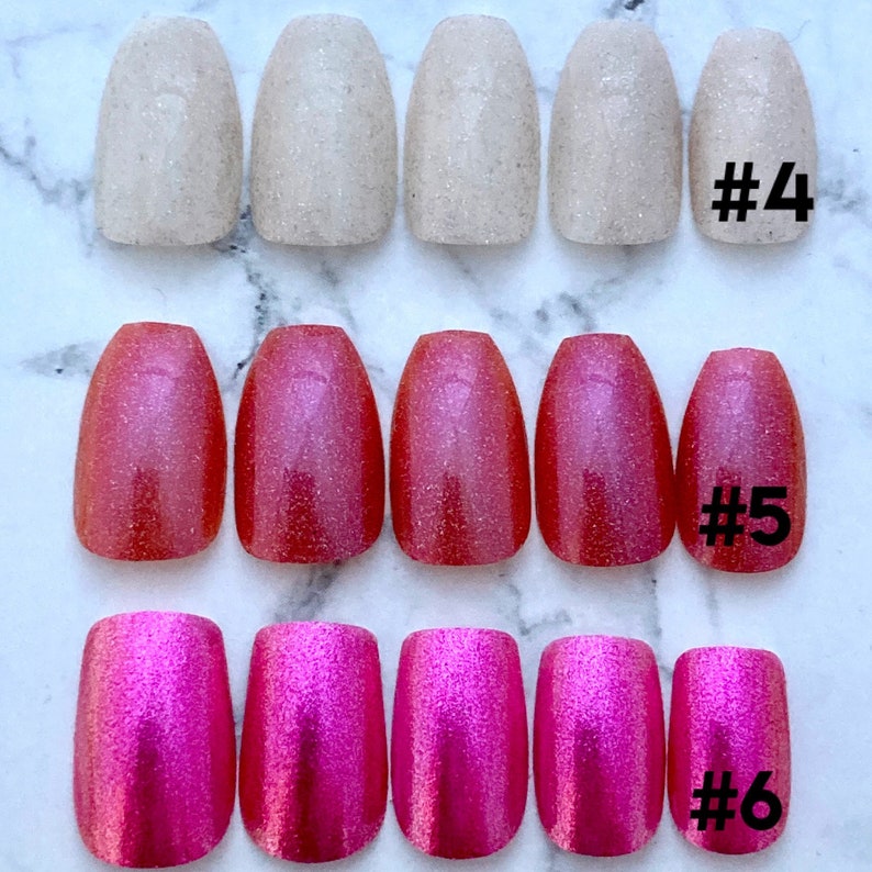 Close shot of various pink press on nails in sets of five to show color options. First row says #4 next to light pink coffin nails, middle shows #5 magenta coffin nails and #6 shows hot pink square nails on a white marble background.