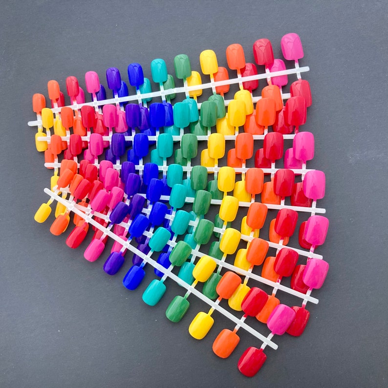 stack of 10 sets of 24 short press on nails in rainbow colors- red, orange, yellow, green, blue, indigo and violet.