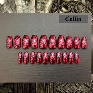 photo shows full set of 20 red coffin shaped nails with black detailing on black background. photo frame is of a gothic church detail. Text on upper right reads coffin.